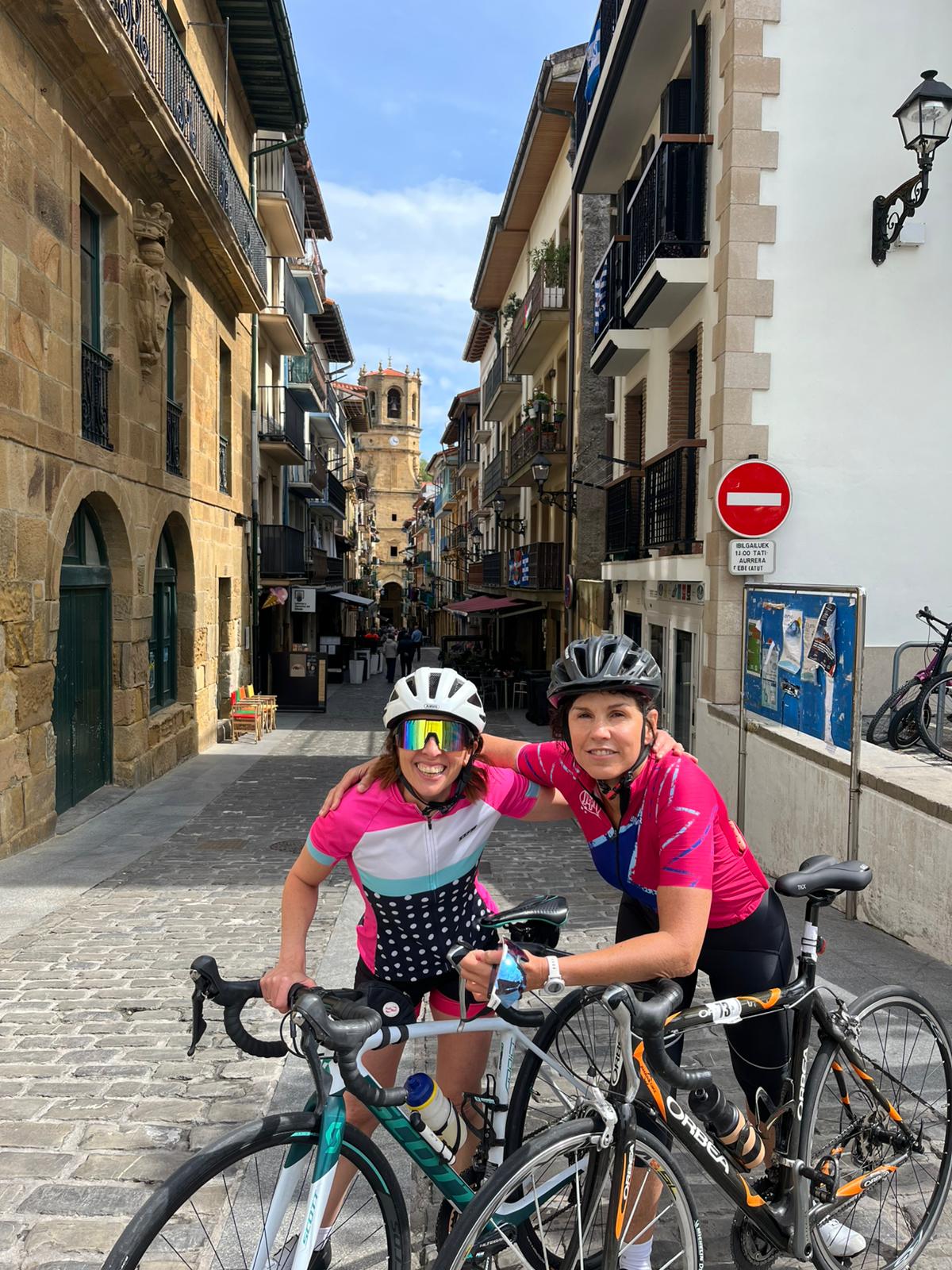 Beti with a friend and their road bikes in an old-town street in the Basque Country