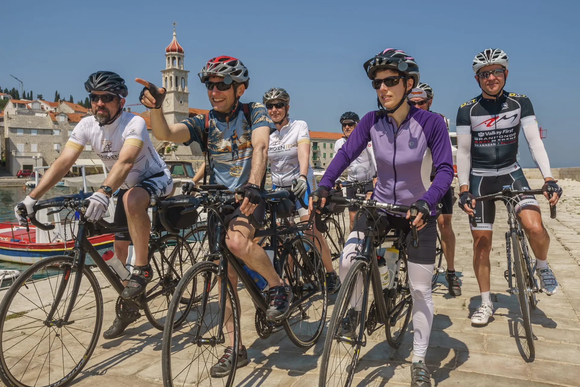 Relaxed group of recreational cyclists smiling together on a harbour front in a coastal town
