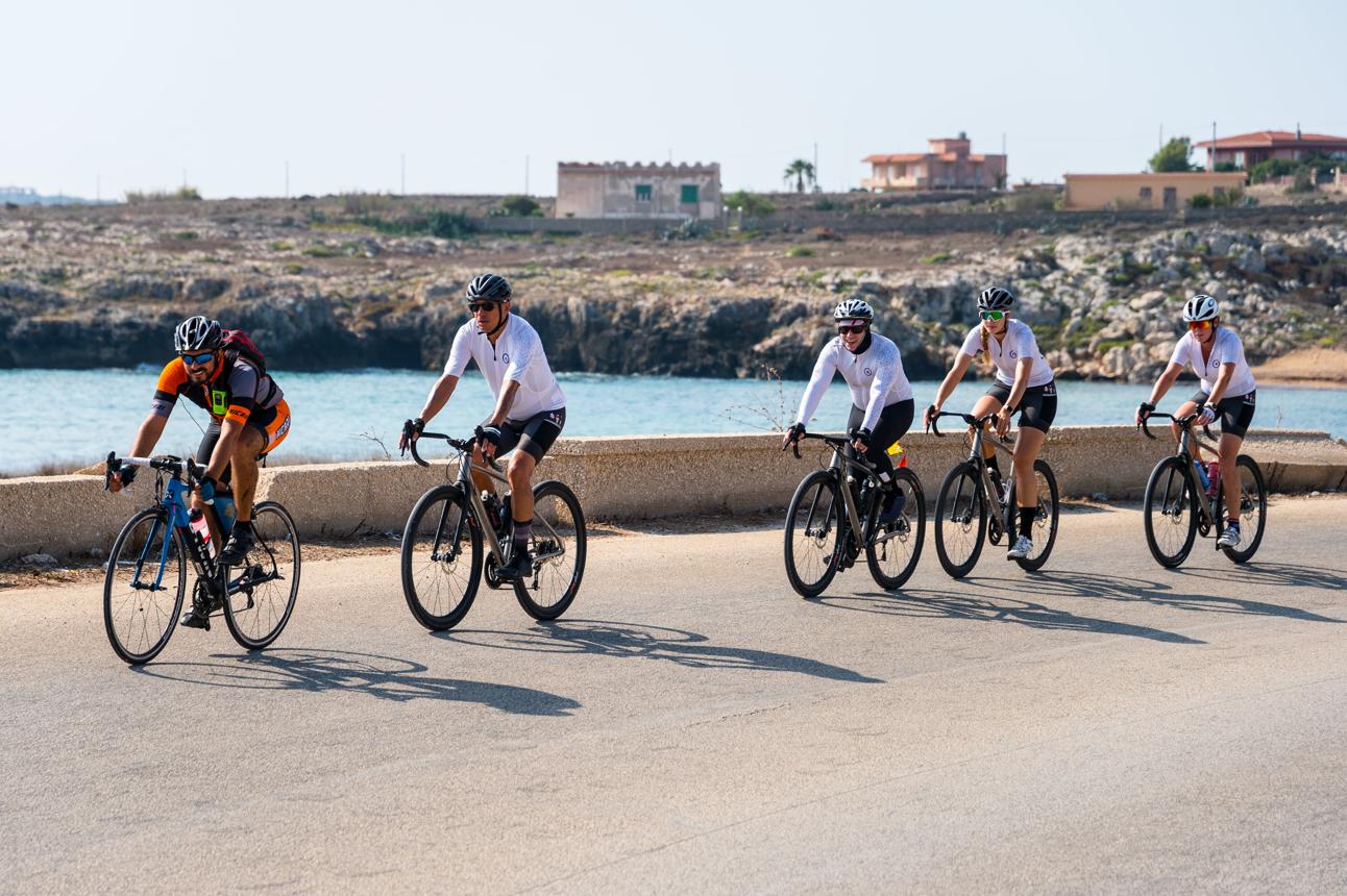 Small group of cyclists riding together along a scenic coastal road